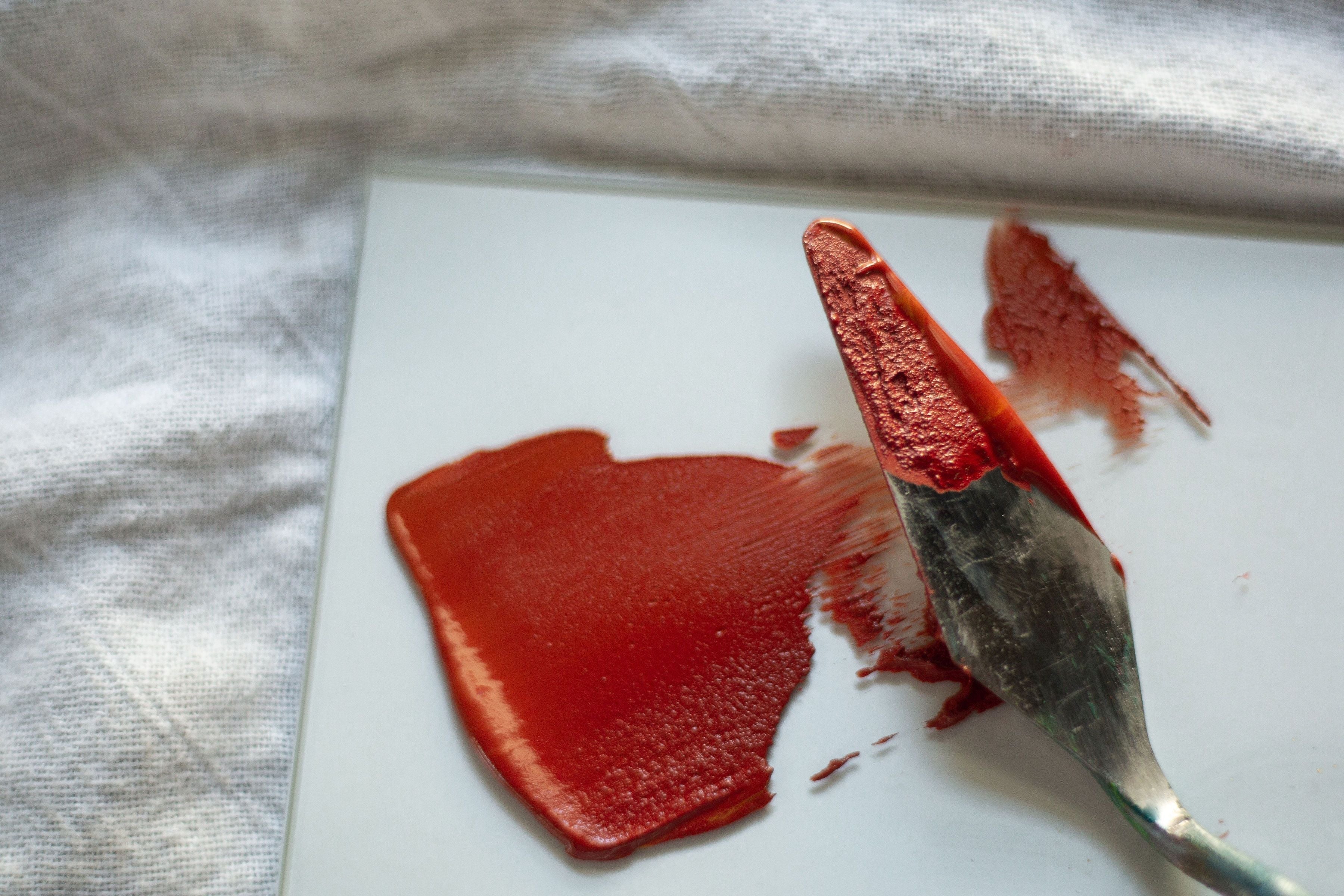 Red paint on a white surface with a brush