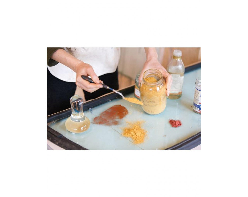 Person preparing pigment on a tray with various ingredients and a Clear Glass Paint Muller 