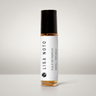 A clear glass rollerball perfume bottle with amber liquid, a black cap, and a white label reading 'LISA NOTO' and 'HUILE DE PARFUM NEROL - PATCHOUli', centered on a light gray background.