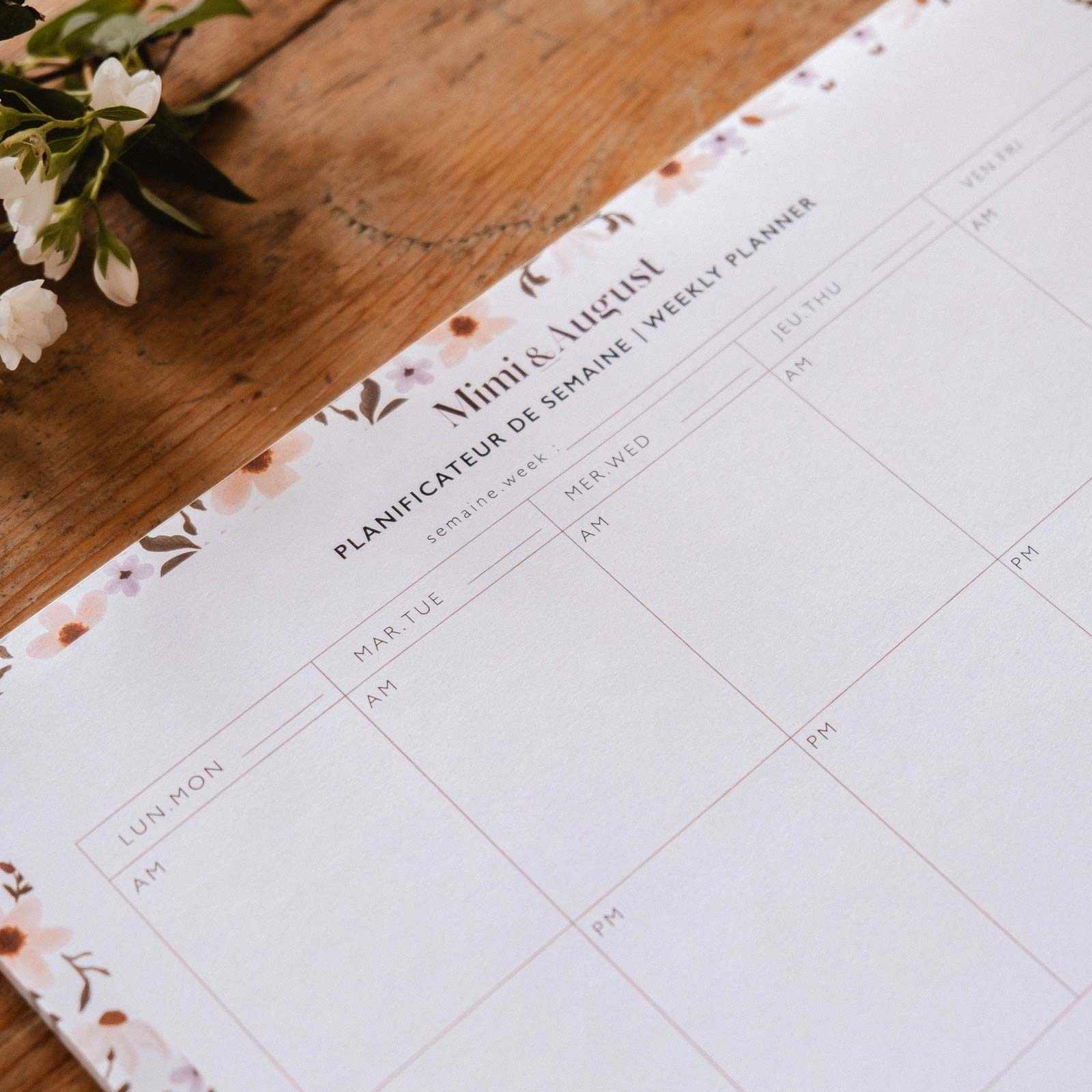 Weekly planner on a wooden surface with floral design