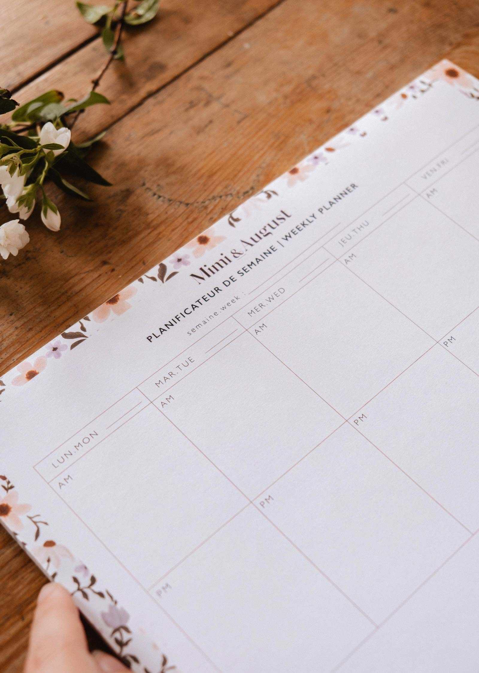 Weekly planner on a wooden surface with floral design