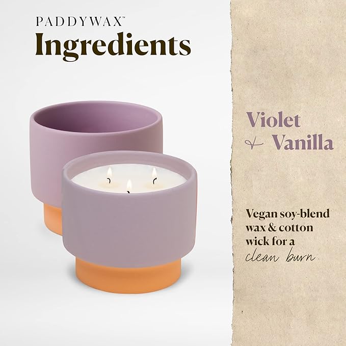 Two candles in purple holders with a beige background and text about ingredients and materials.