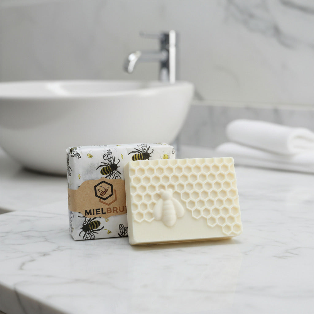 Bar of soap with honeycomb design on a marble surface, with packaging labeled 'Mielbré' in the background.