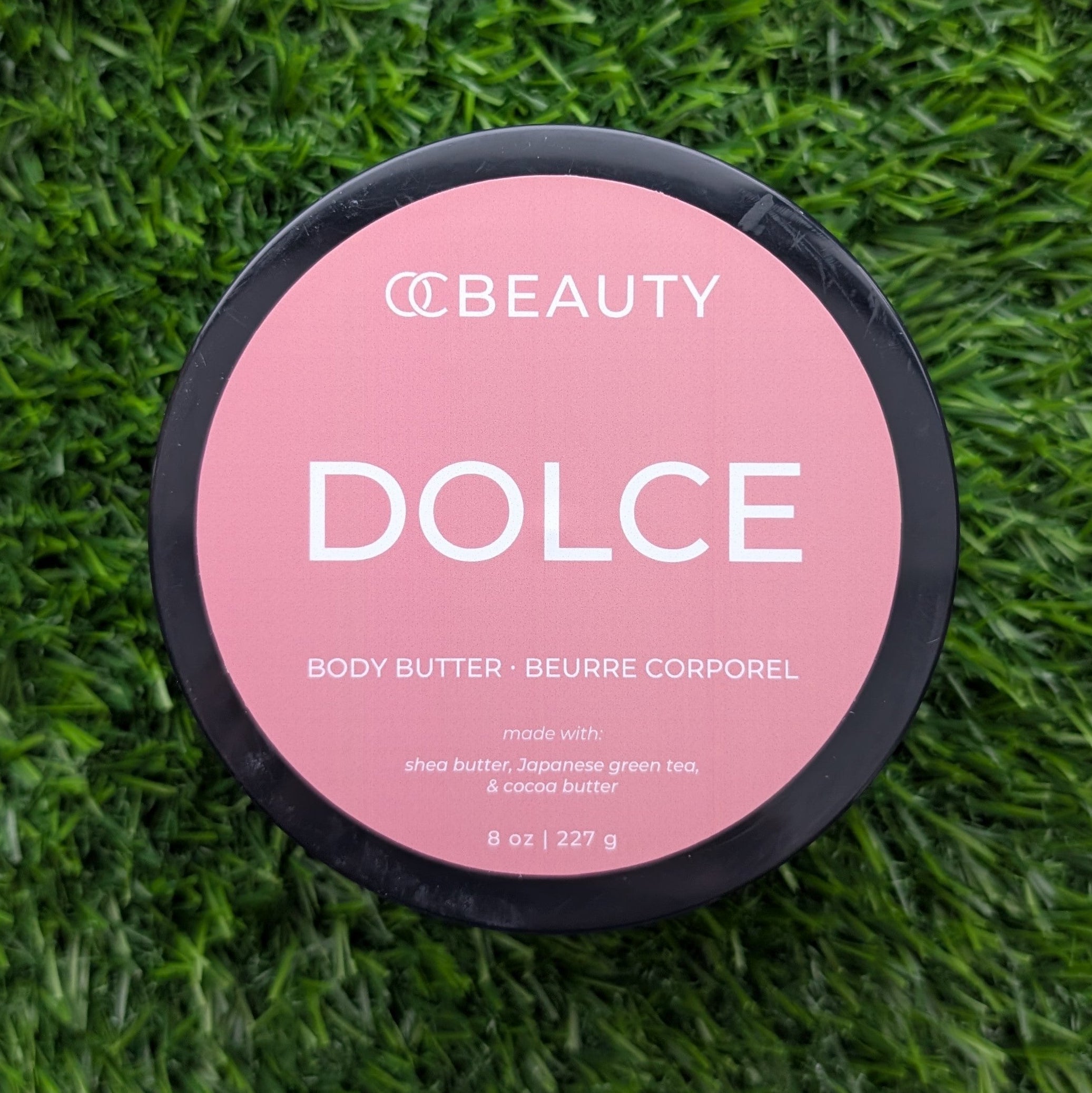 OC Beauty Body butter container labeled 'Dolce' on a grass background