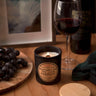 Stopandsmellthecandles Niagara on the Lake Cabernet soy candle – 8 oz black jar with lit wooden wick and wooden lid beside grapes and red wine