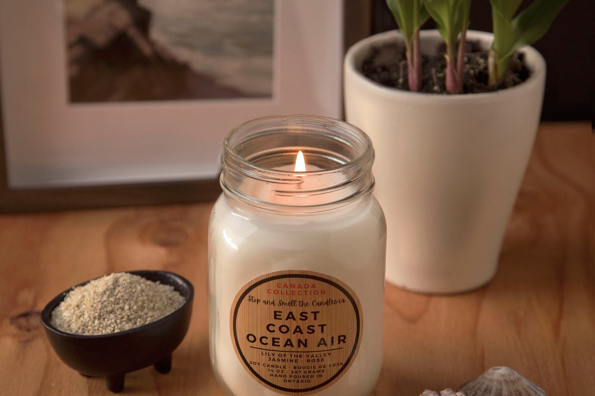 Candle with 'East Coast Ocean Air' label on a wooden surface with decorative items 