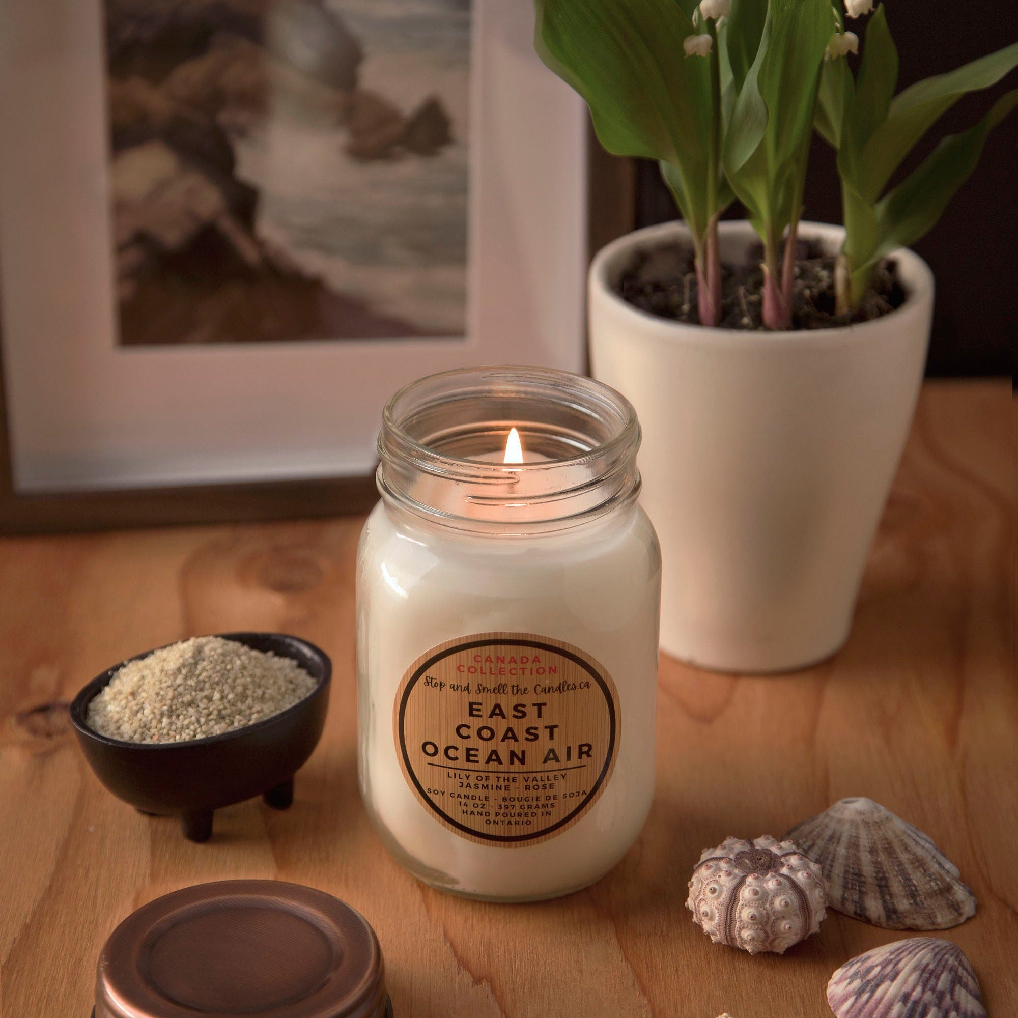 Candle with 'East Coast Ocean Air' label on a wooden surface with decorative items 