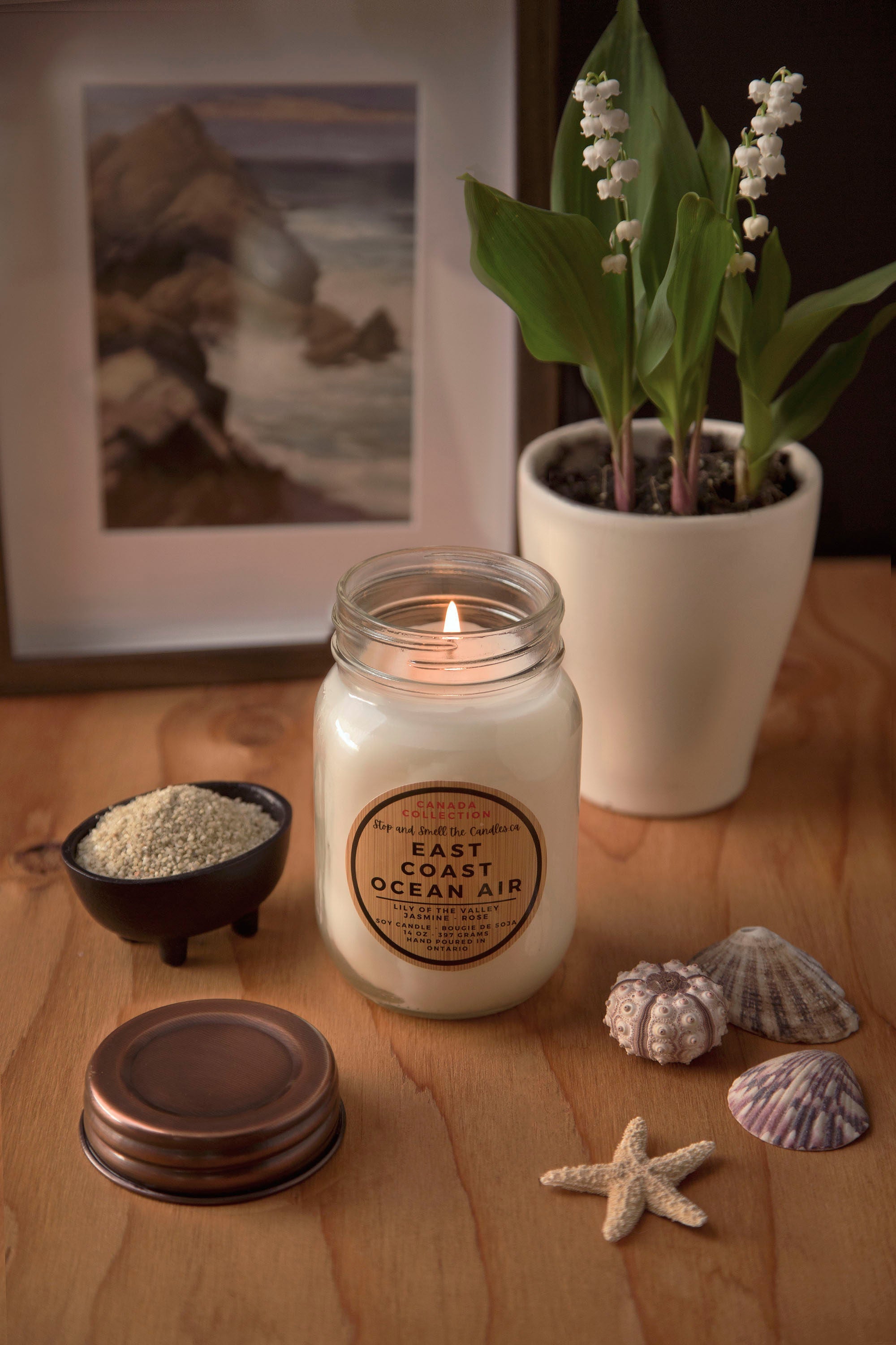 Candle with 'East Coast Ocean Air' label on a wooden surface with decorative items 