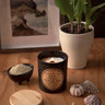 Candle labeled 'Ocean Air' on a wooden surface with a plant, shells, and a starfish.