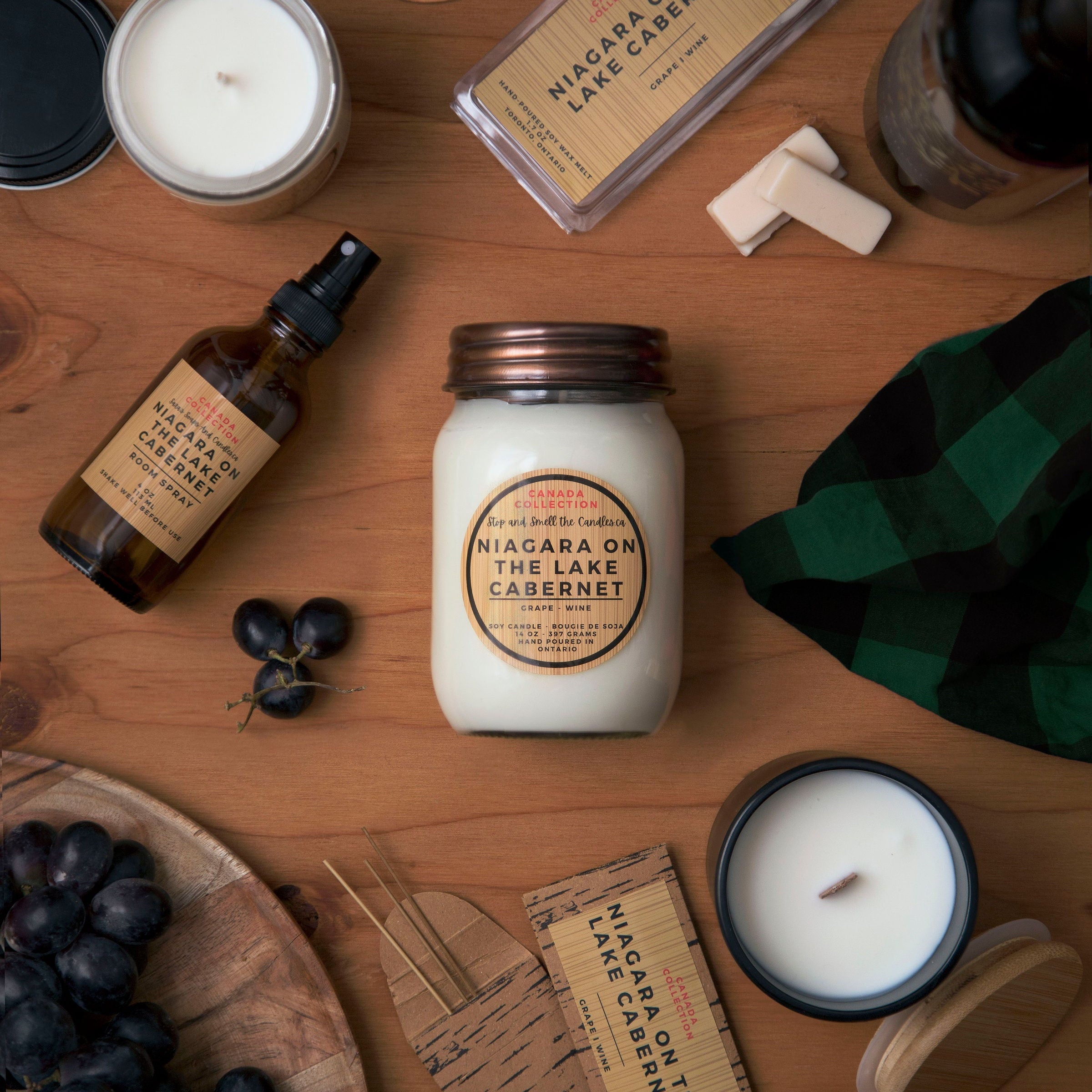 Assorted products including candles, bottles, and a jar on a wooden surface.