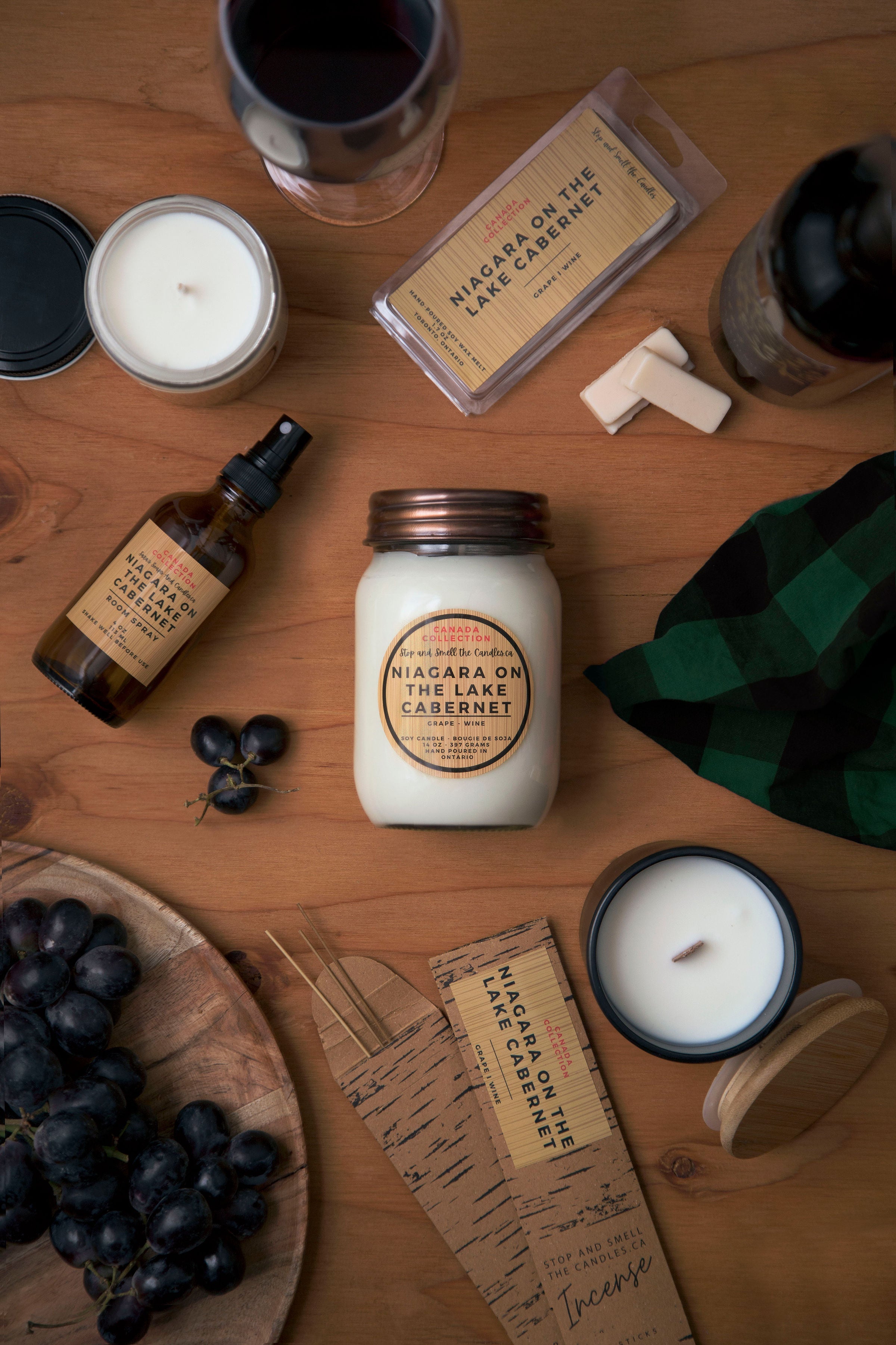 Assorted products including candles, bottles, and a jar on a wooden surface.