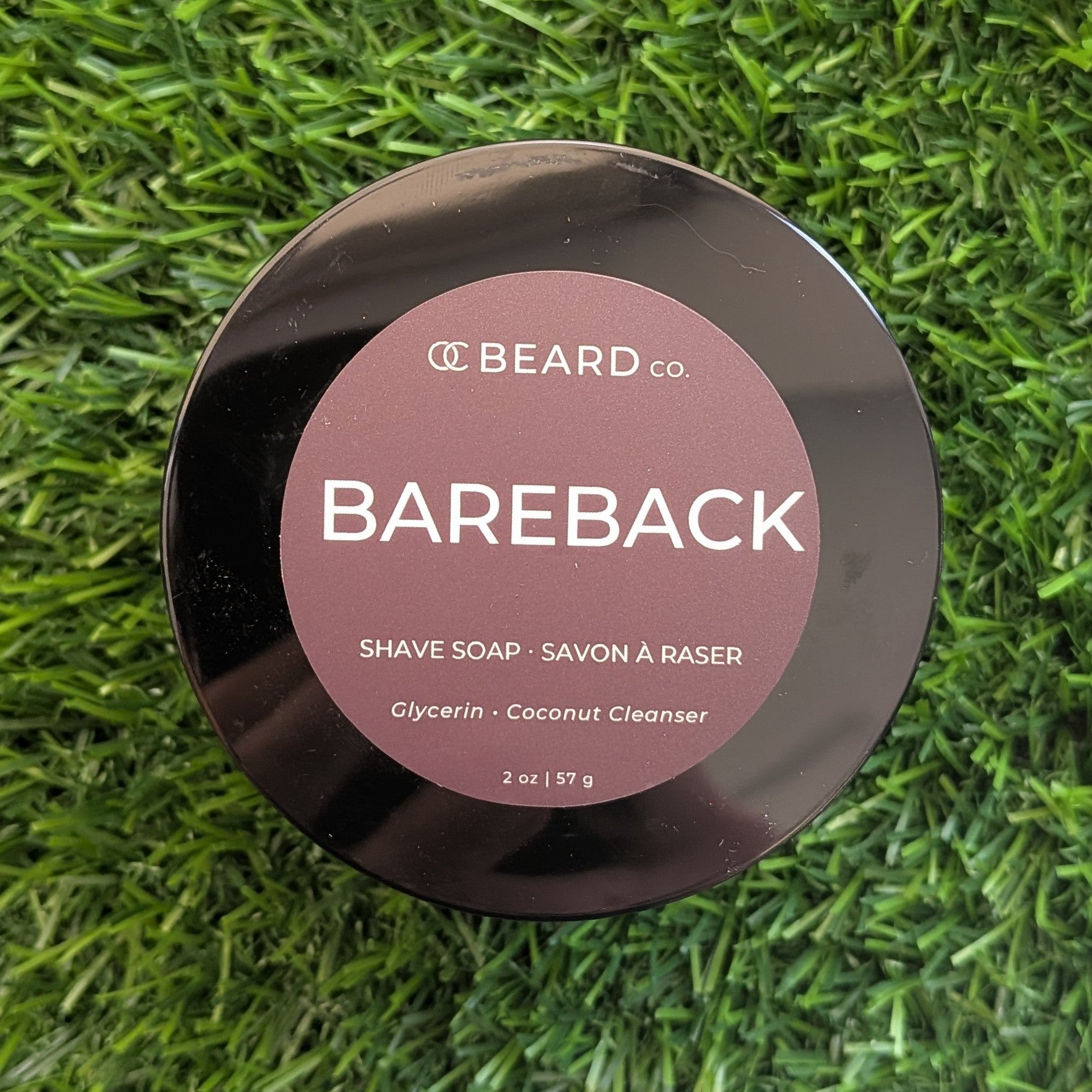 Shave soap container labeled 'Bareback' by OC Beard Co. on a grass background
