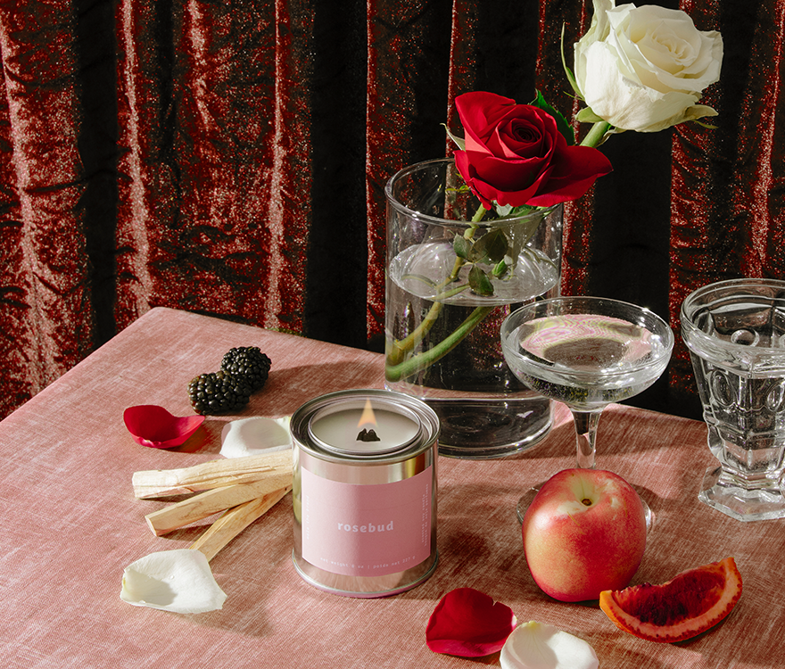 Candle, flowers, and fruit on a table with a red curtain background
