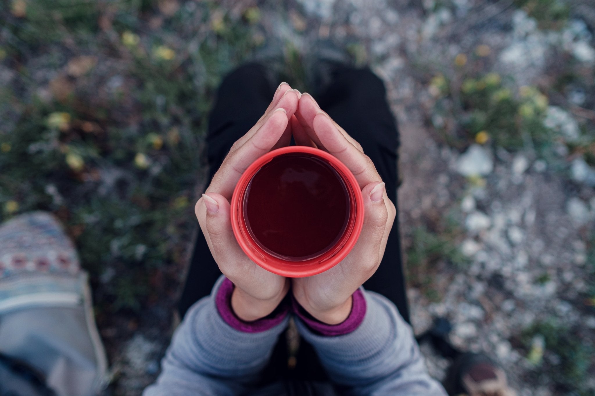 Person holding a red cup with a natural outdoor background