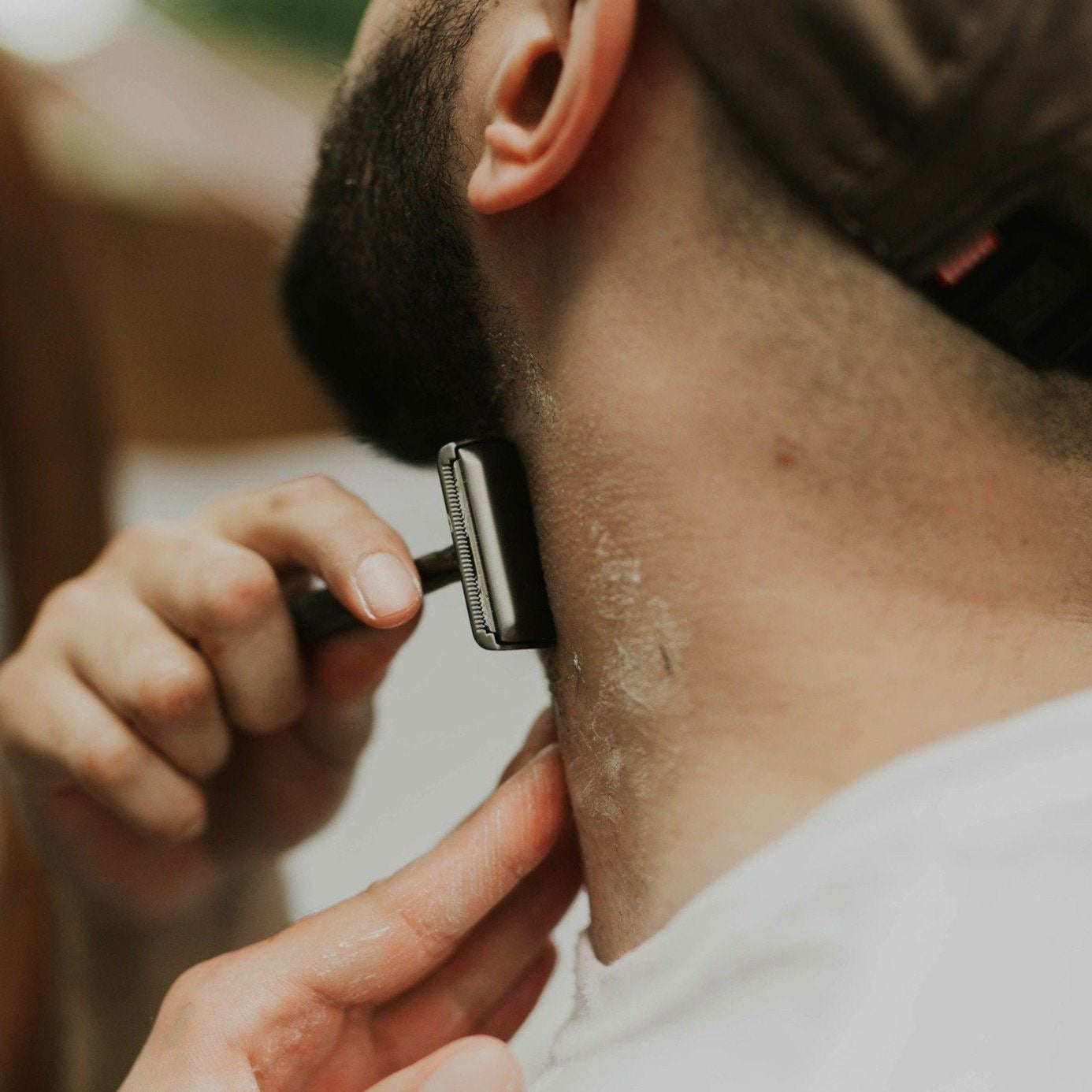 Person shaving their neck with a razor