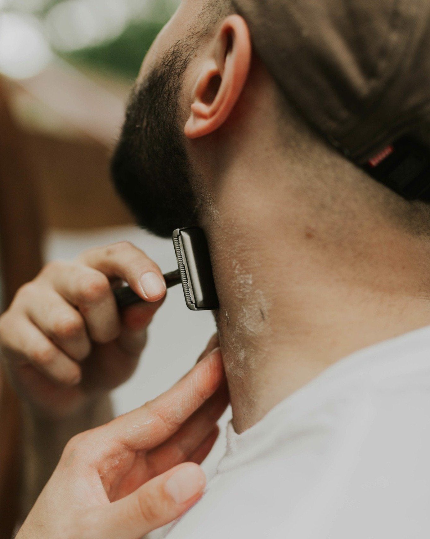 Person shaving their neck with a razor