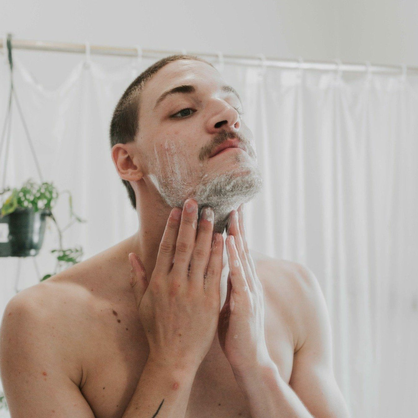 Man applying shaving cream to his face in a bathroom.