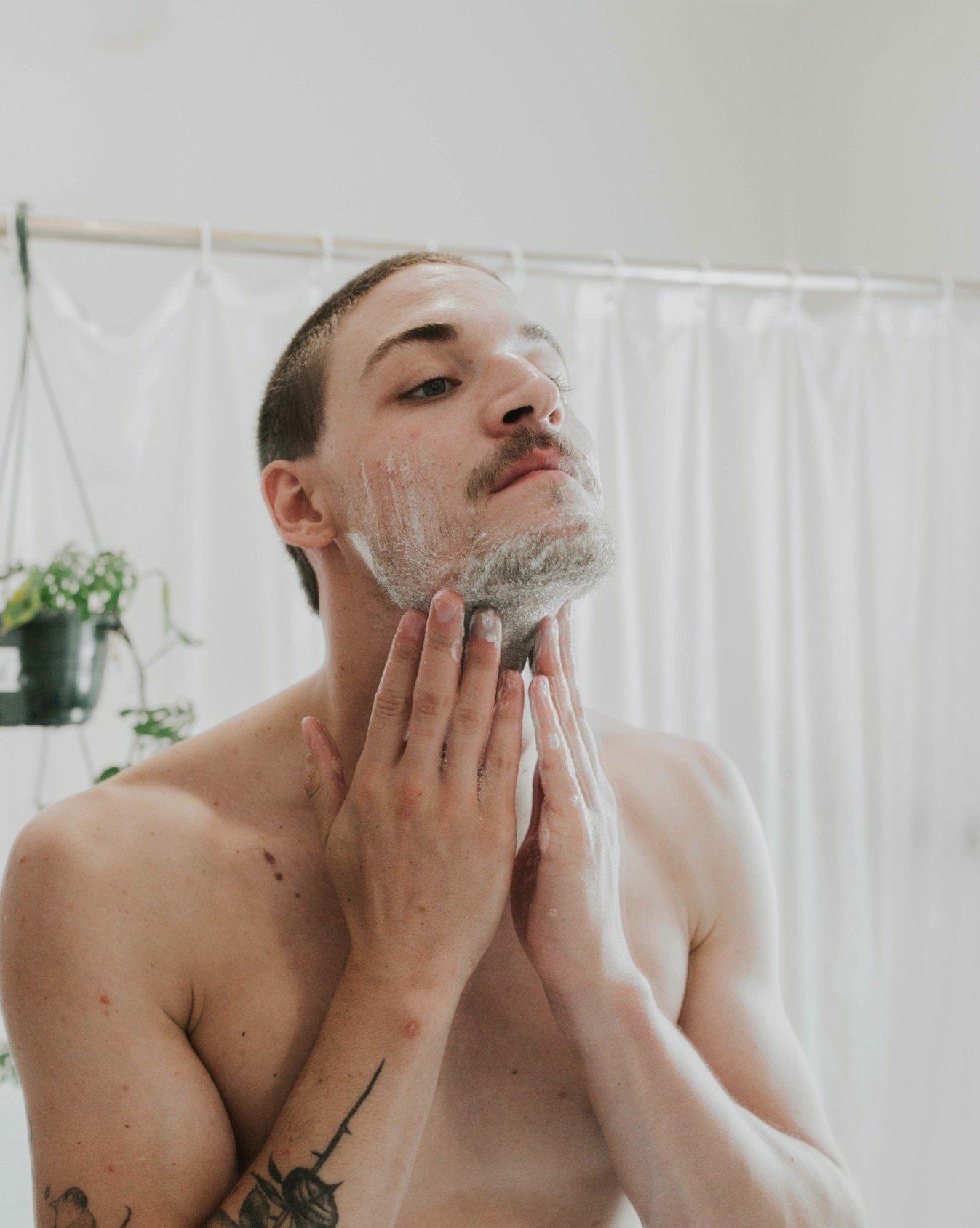 Man applying shaving cream to his face in a bathroom.