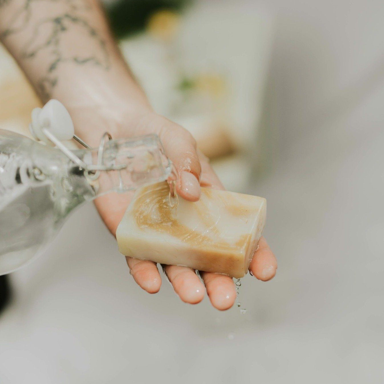 Hand holding a bar of soap with water droplets, blurred background