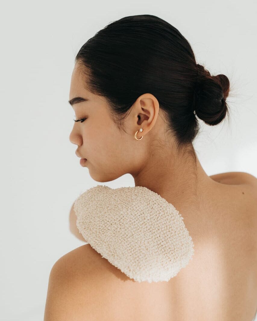 Woman with a textured cream pad on her shoulder against a white background