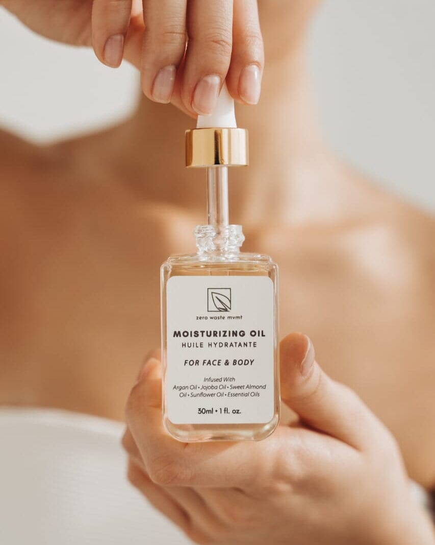 Hand holding a bottle of moisturizing oil with a blurred background