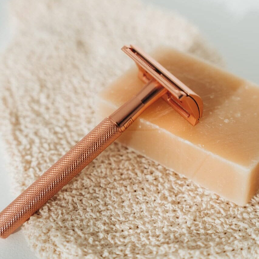 Rose gold safety razor on a bar of soap with a soft background