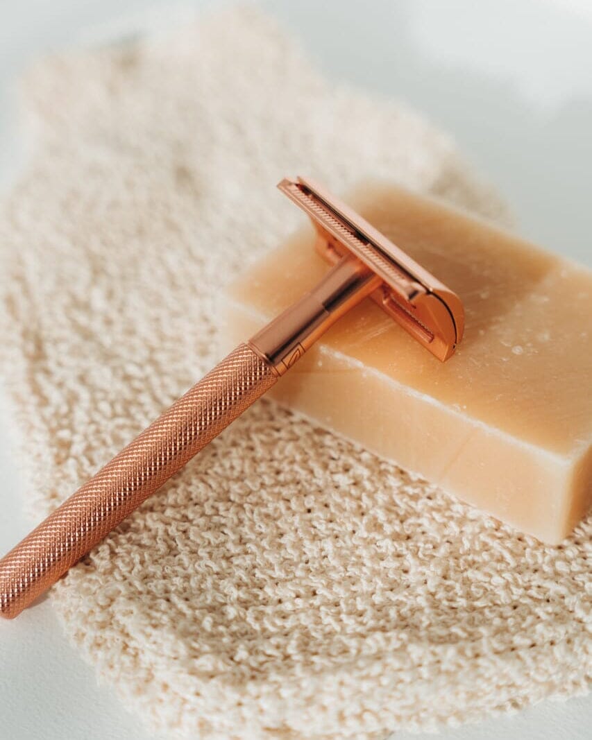 Rose gold safety razor on a bar of soap with a soft background