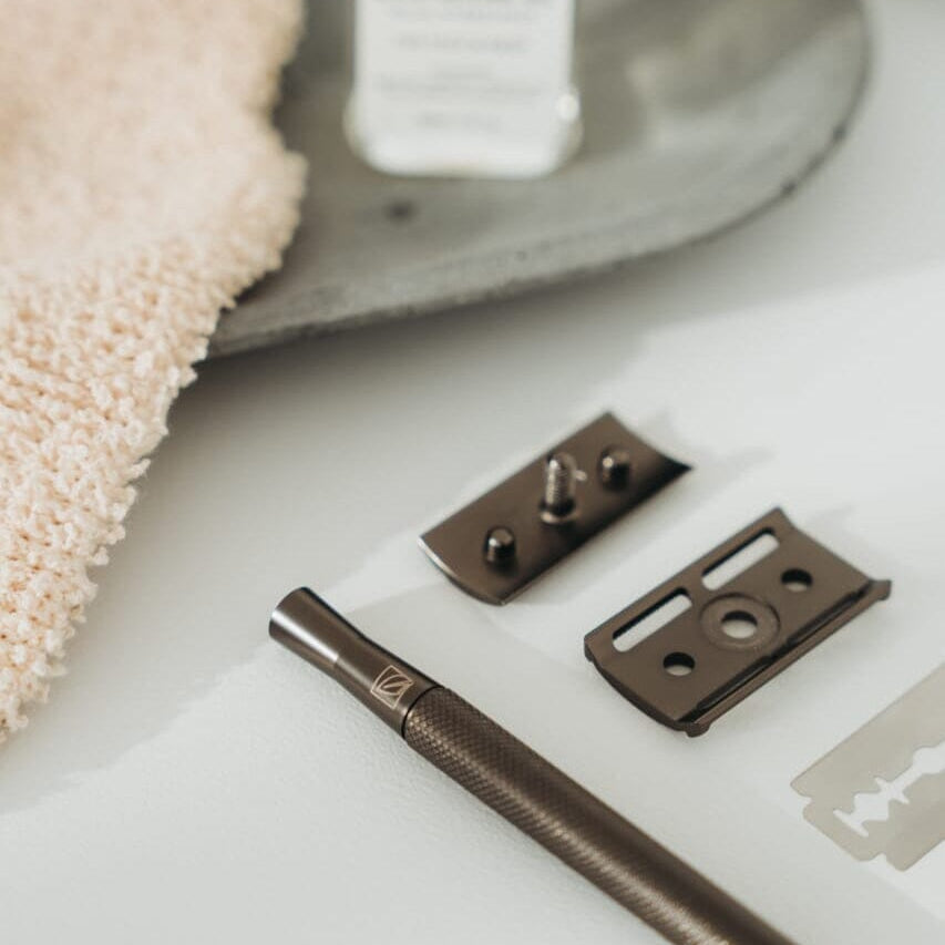 Bronze door handle and lock mechanism on a white surface with a towel and soap bar in the background.