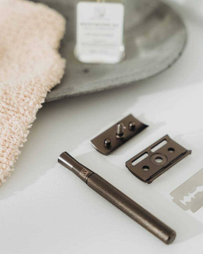 Bronze door handle and lock mechanism on a white surface with a towel and soap bar in the background.