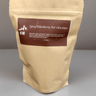Kraft paper packaging of Spicy Elderberry Hot Chocolate with a brown label on a gray background