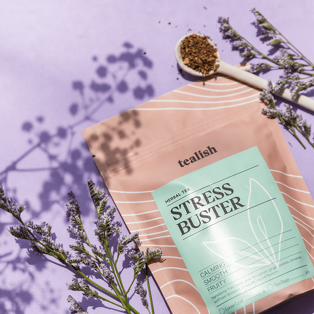 Tealish Stress Buster herbal tea package with dried herbs on a purple background