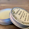 Tallow balm in a metal tin with a label on a wooden surface