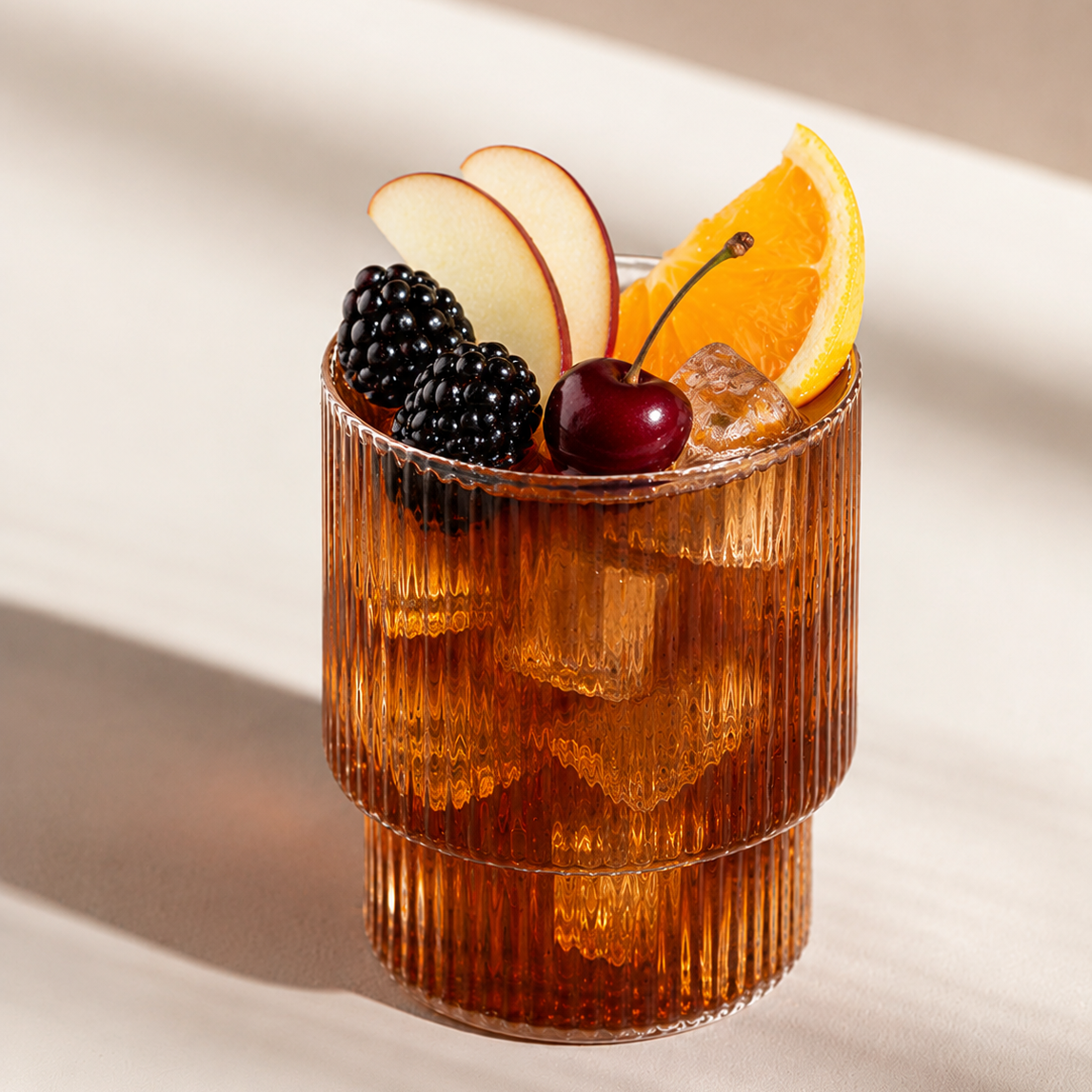 Cocktail in a ribbed glass with fruit and ice on a light background