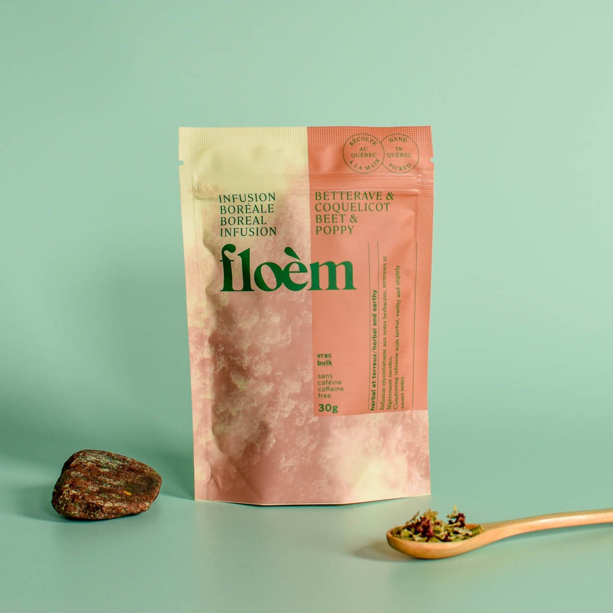 floèm tea package with a spoonful of tea and a rock on a light green background