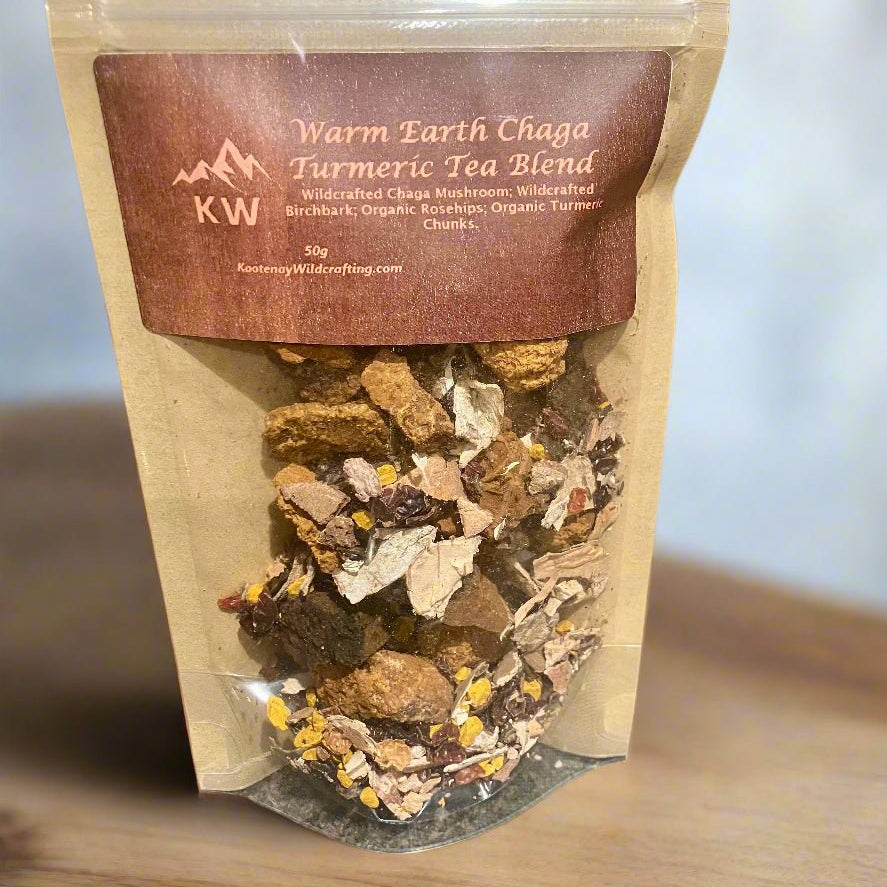 Package of Warm Earth Chaga Turmeric Tea Blend with visible tea leaves on a wooden surface.